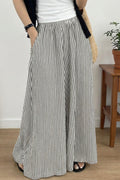 Person wearing a black and white striped skirt with a plain background
